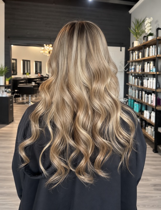 Long blonde waves with darker roots, viewed from behind — AI-retouched image